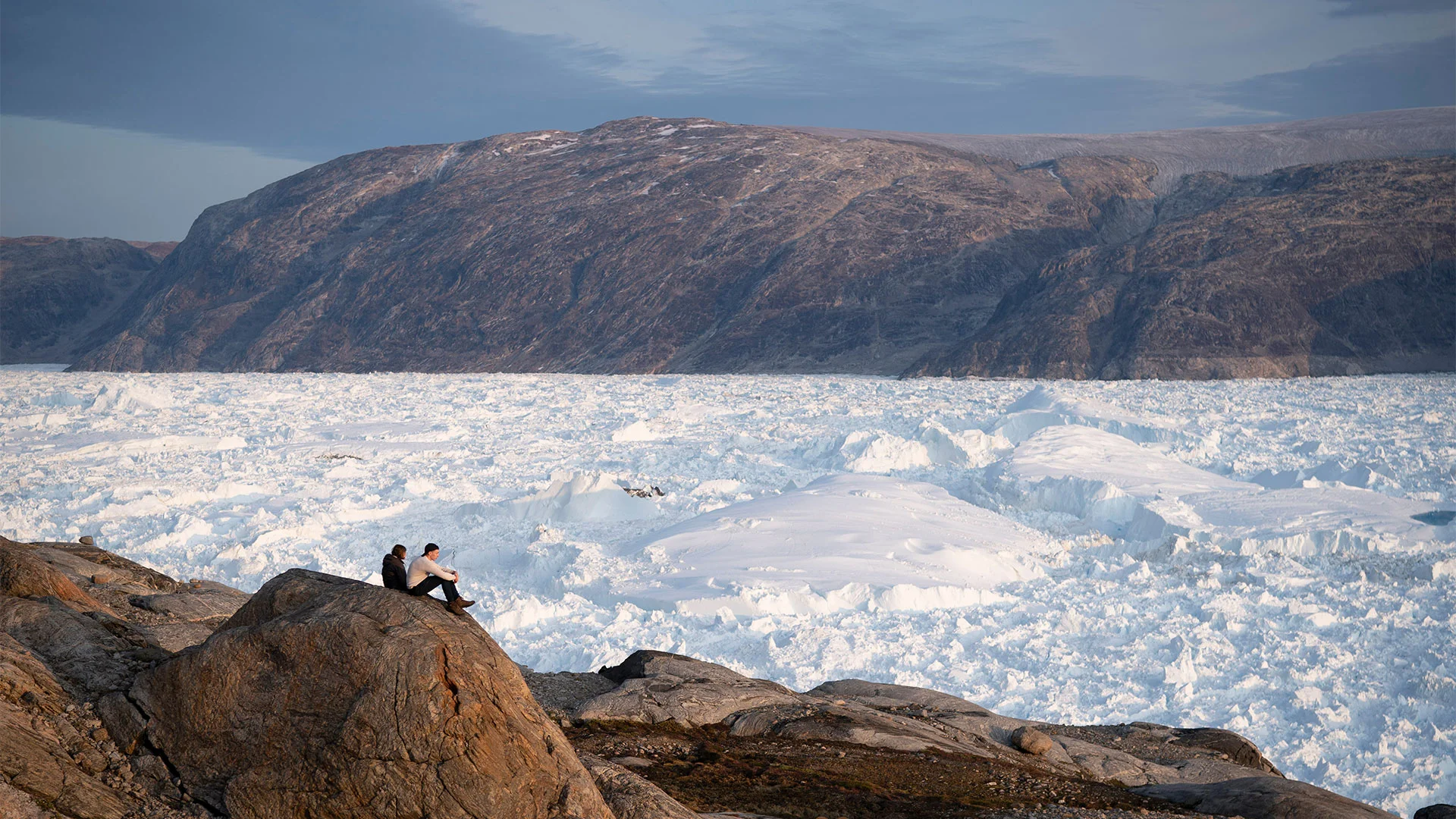 Estudiantes investigadores de la Universidad de Nueva York (NYU) se sientan sobre una roca con vistas al glaciar Helheim en Groenlandia, el 16 de agosto de 2019. [Foto: Felipe Dana/AP Photo]

