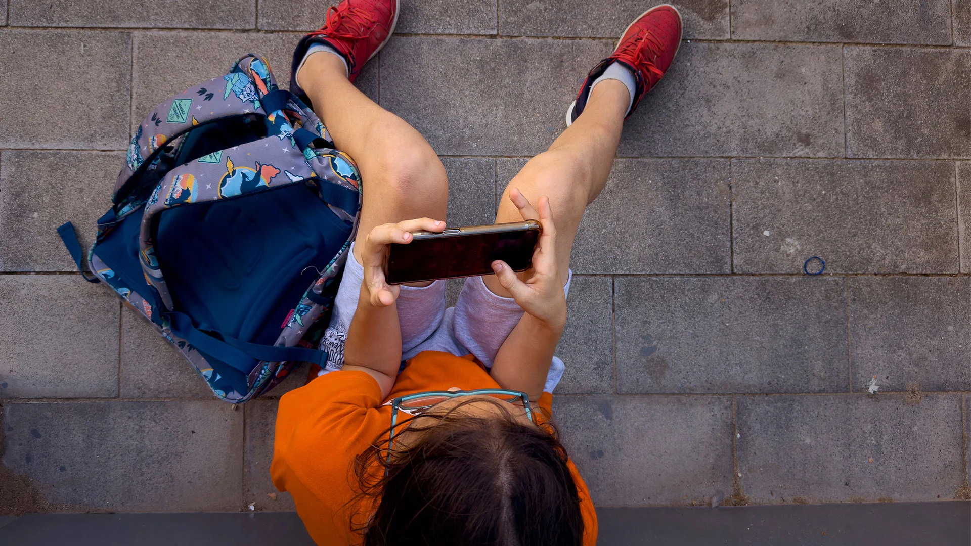 ARCHIVO – Un niño juega con el teléfono de su padre frente a una escuela en Barcelona, ​​España, el lunes 17 de junio de 2024. [Foto: Emilio Morenatti, Archivo/AP Photo]

